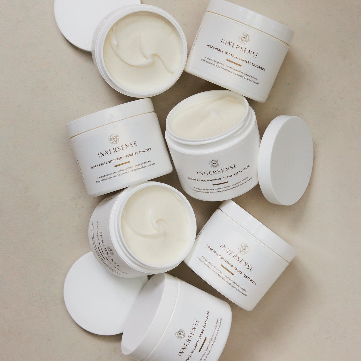 Multiple jars of Innersense cream on a beige background