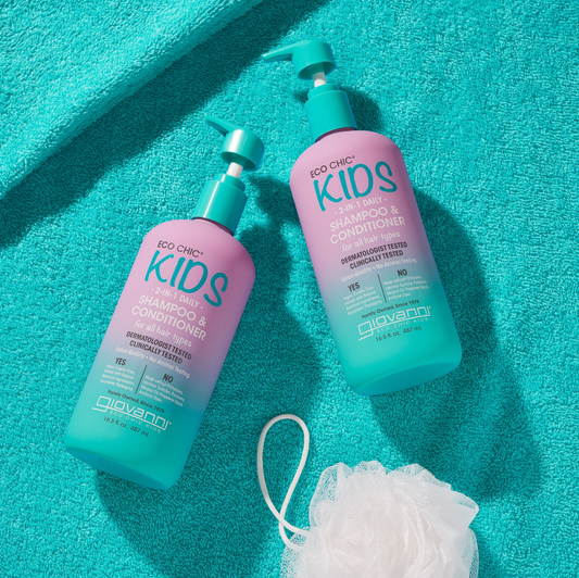 Two bottles of Giovanni Kids shampoo and conditioner on a turquoise towel with a loofah.