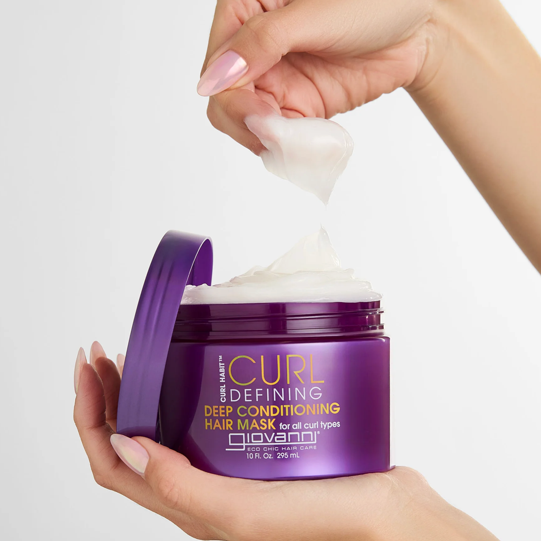 Purple jar of Giovanni Curl Defining Deep Conditioning Hair Mask with a hand scooping out the cream.