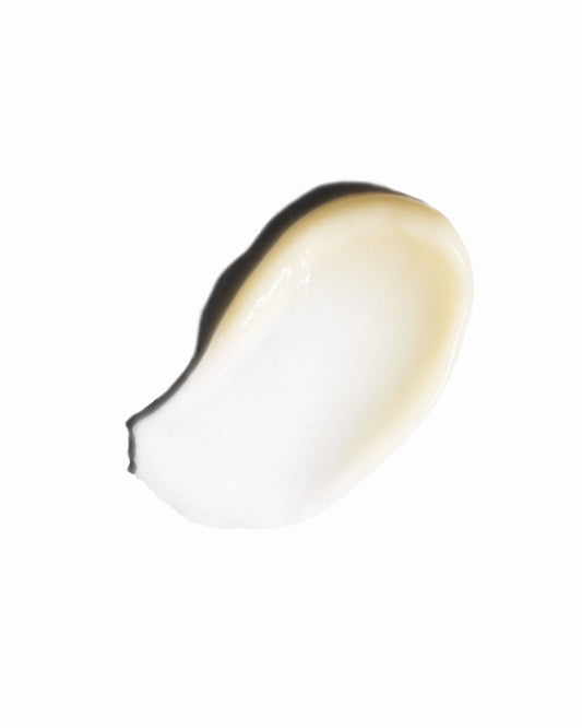 A dollop of creamy, semi-translucent cosmetic product, showing a warm beige-tan shade with a dark edge, isolated on a solid white background.