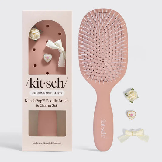 Pink paddle brush with 'kitsch' branding next to its packaging on a white background