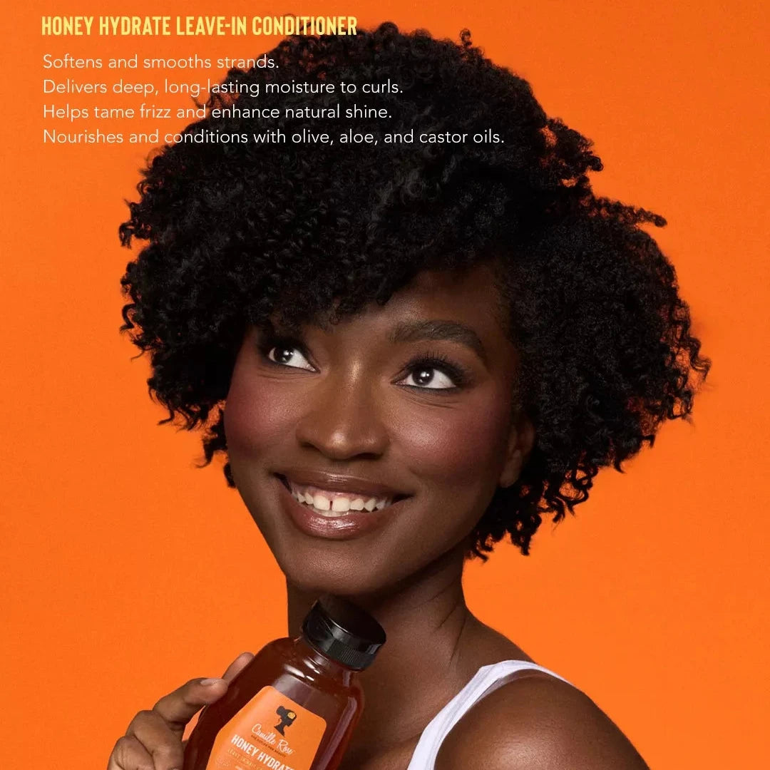 Woman holding a bottle of Honey Hydrate Leave-In Conditioner against an orange background