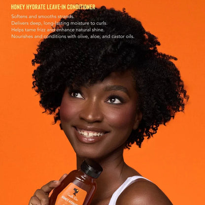 Woman holding a bottle of Honey Hydrate Leave-In Conditioner against an orange background