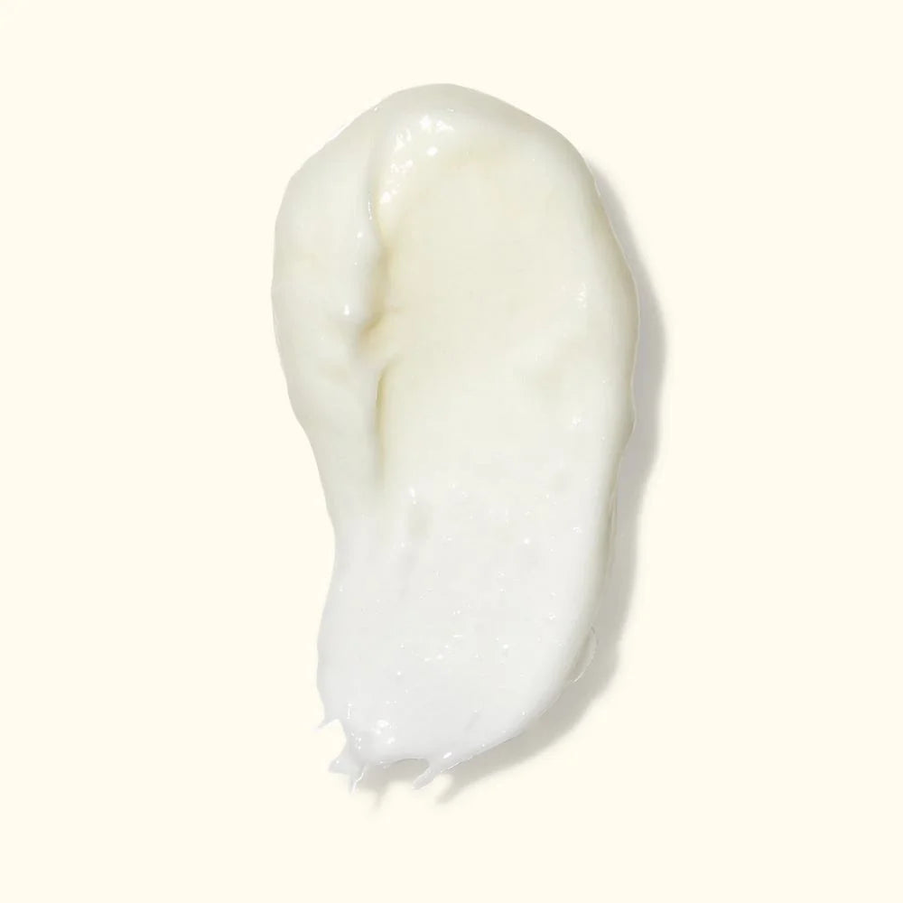 A dollop of thick, creamy white lotion or serum on a solid off-white background.