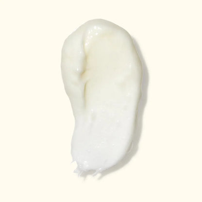 A dollop of thick, creamy white lotion or serum on a solid off-white background.