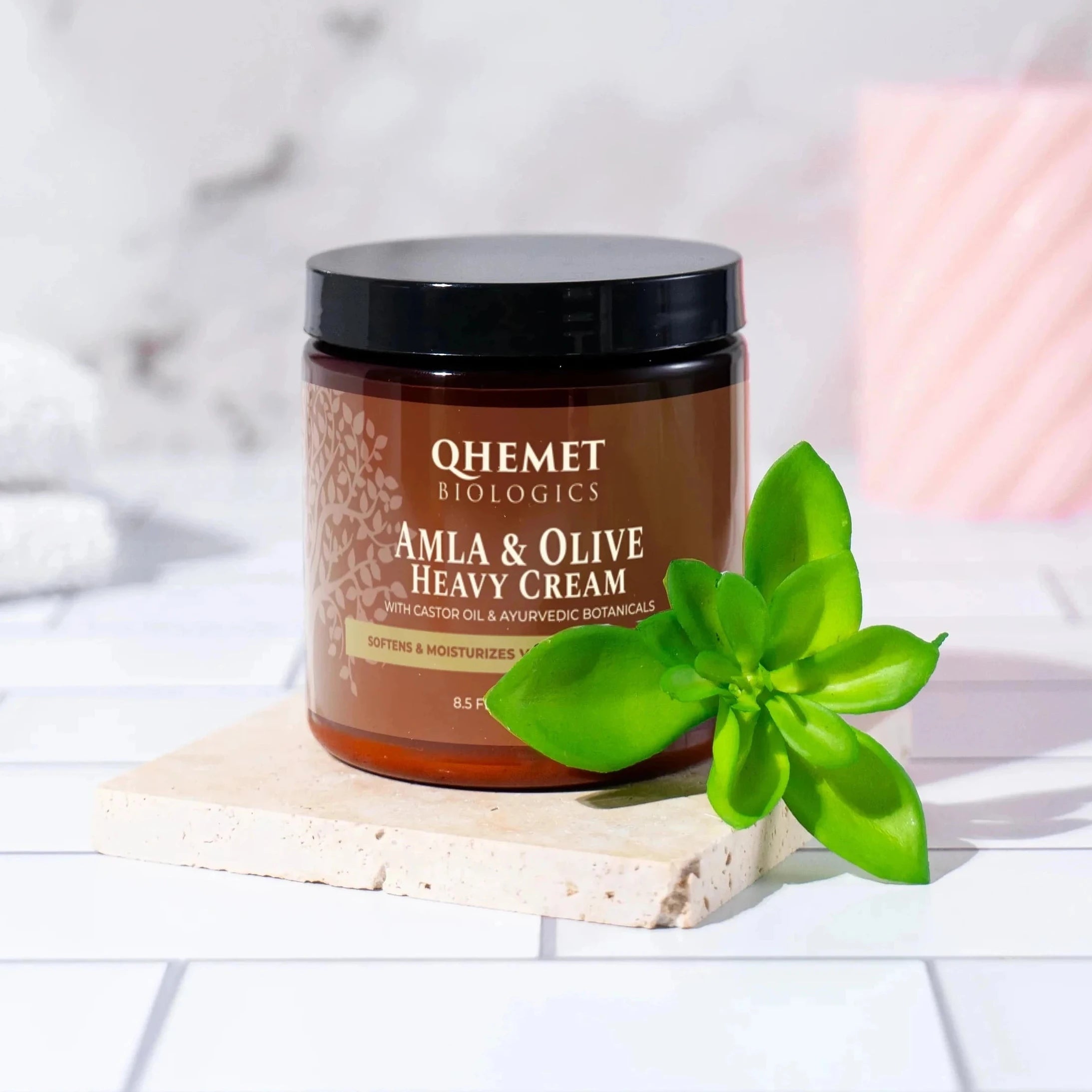 Jar of cream on a bathroom counter with towels and soap in the background