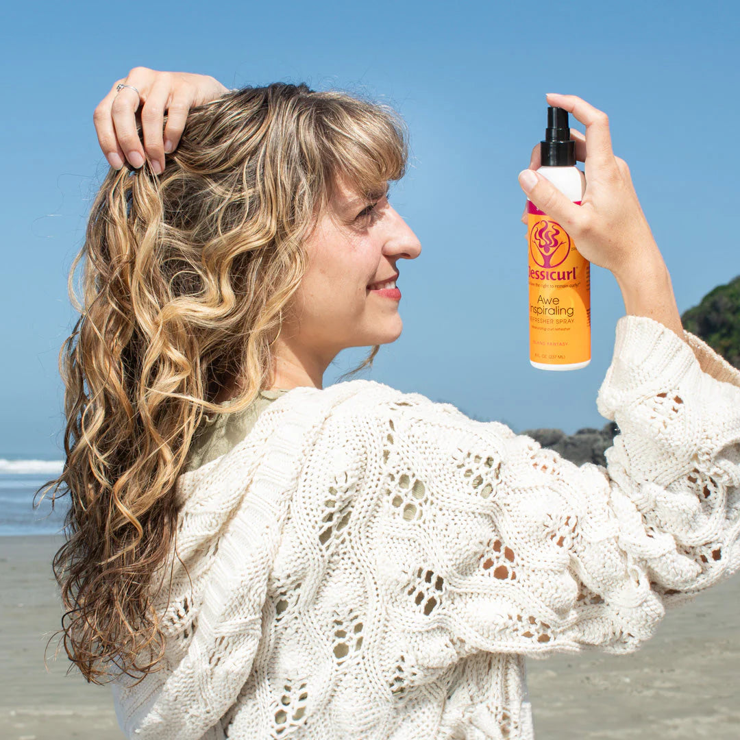 Woman applying hair product spray on beach