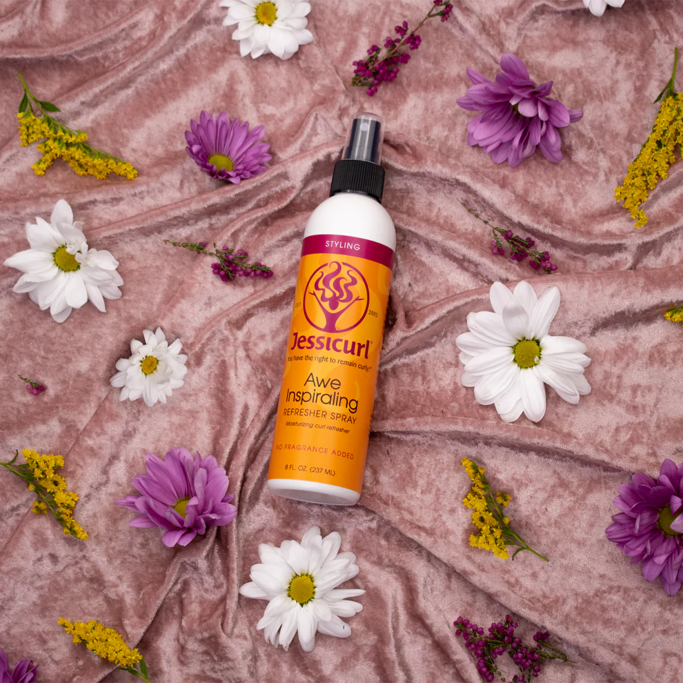 Jessicurl hair product bottle surrounded by flowers on a textured pink background