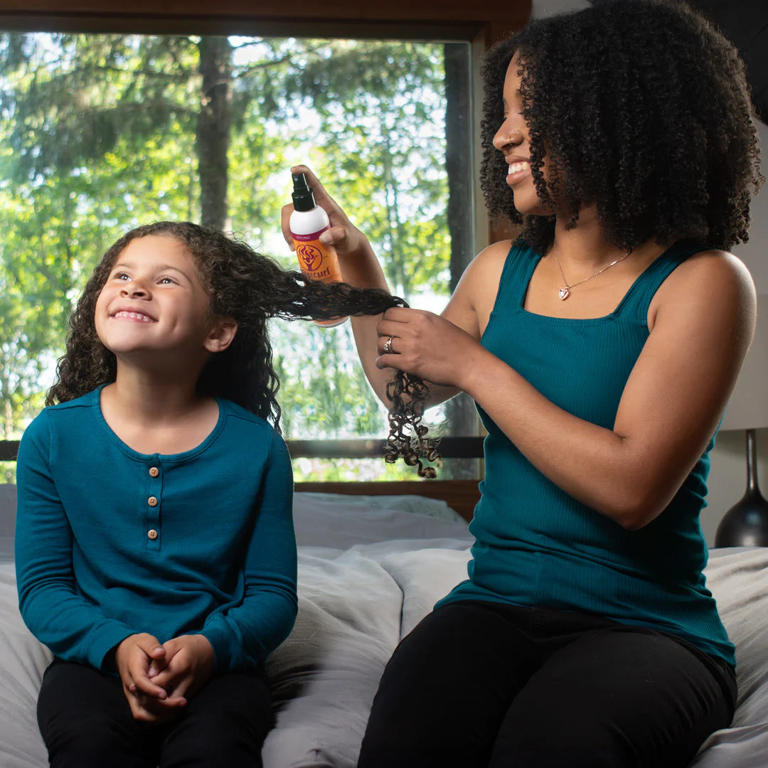 Woman and child sitting on a couch with a window showing greenery outside