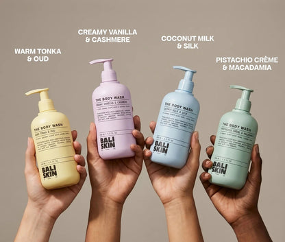 Four pump bottles of Bali Skin body wash are held up by four hands against a warm beige background. Each hand holds a different colored bottle: yellow, lavender, light blue, and sage green.