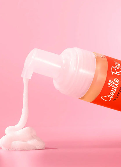Mousse being pumped from a bottle on a pink background