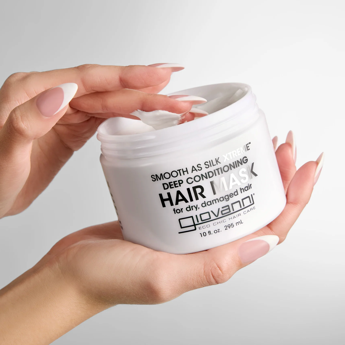 Hand holding a jar of Giovanni hair mask against a neutral background