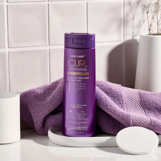 Purple bottle of Curl Habit conditioner on a white surface with a purple towel.