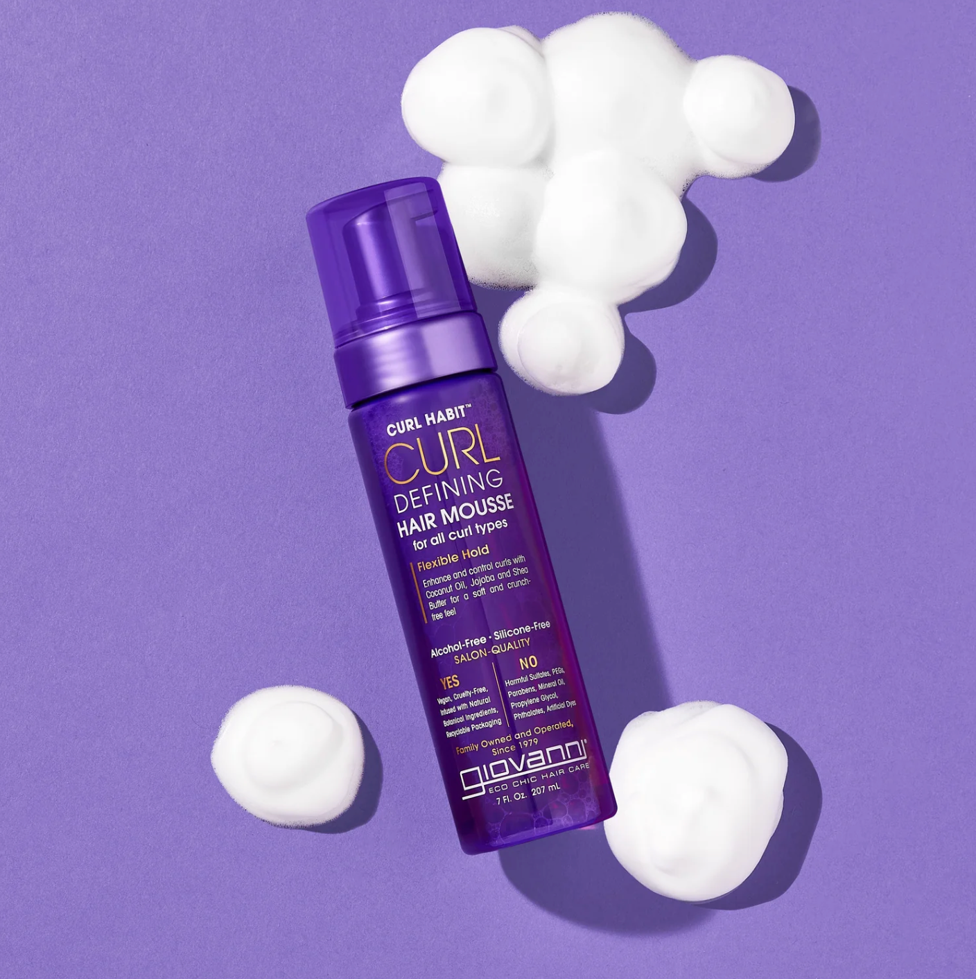 Purple bottle of Curl Defining Hair Mousse with white foam on a purple background