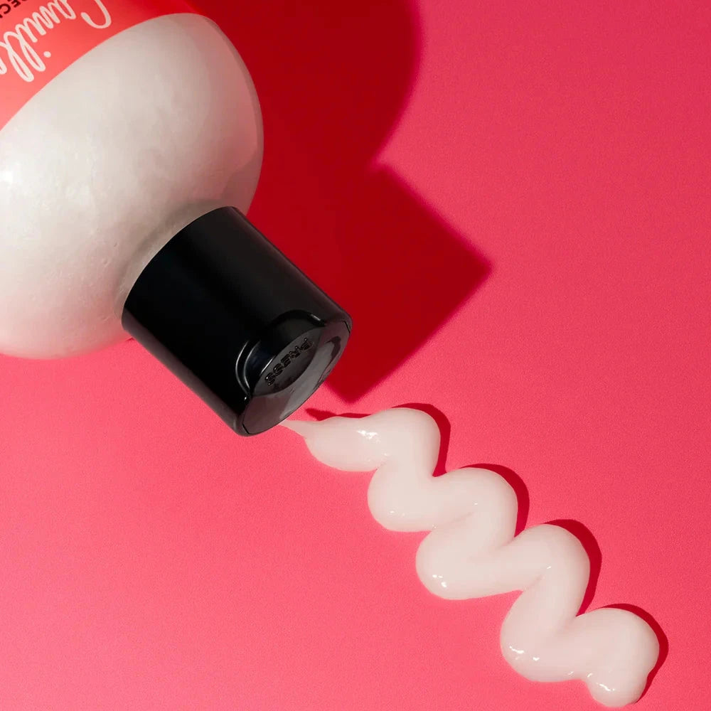 bottle with a wavy line of cream on a pink background