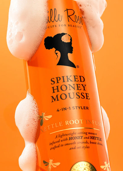 Orange bottle of Camille Rose Spiked Honey Mousse against an orange background