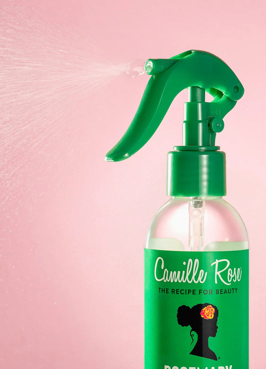 Green spray bottle labeled 'Camille Rose' on a pink background