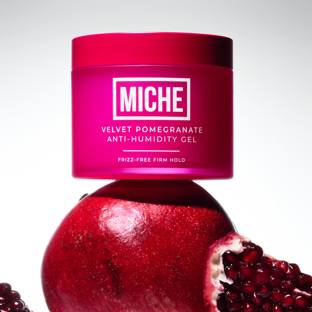 Pink jar of 'MICHE' gel with pomegranate fruit on a white background