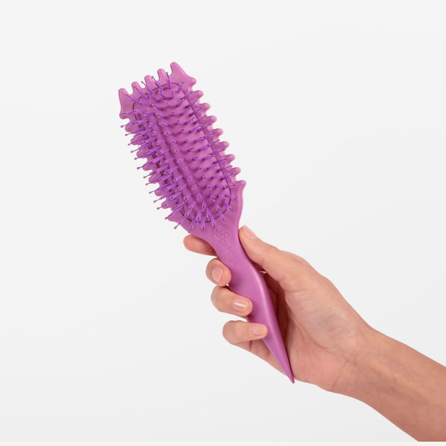 Purple hairbrush held by a hand on a light gray background
