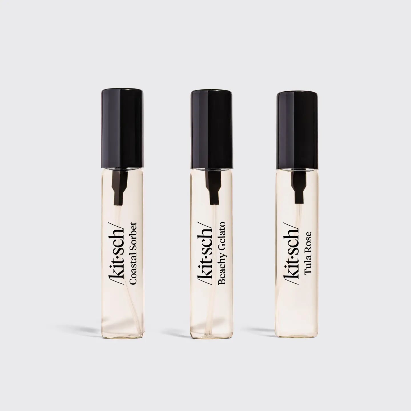 Three Kitsch perfume bottles on a light gray background